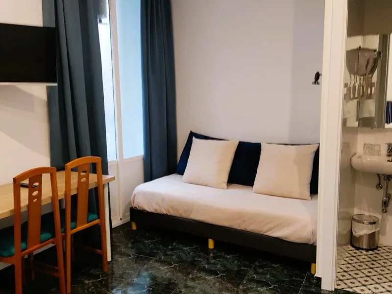 Habitación con sofá, escritorio, televisión y baño en el Hostal Bruña